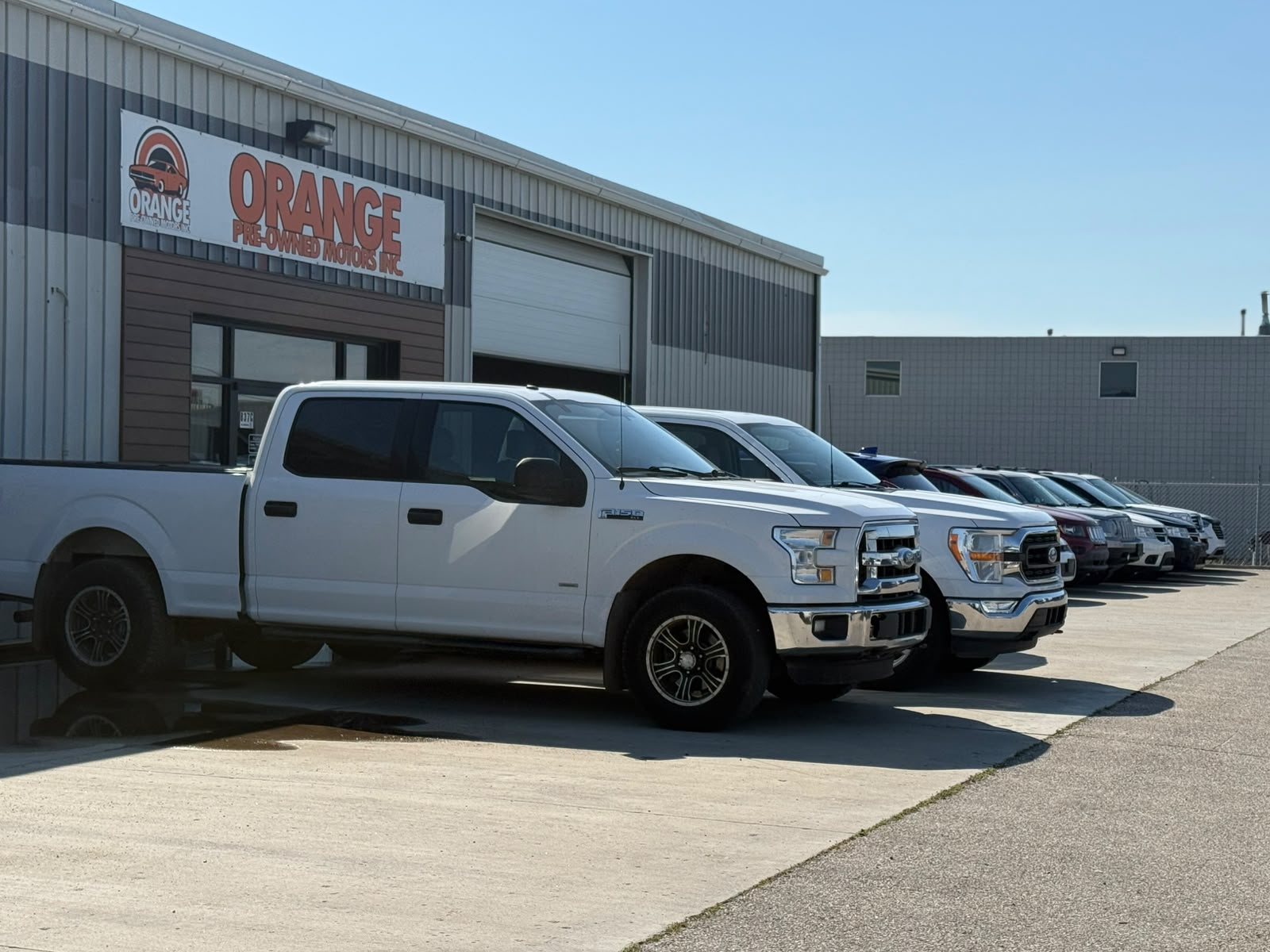 Orange Pre-owned Motors storefront and vehicle lot